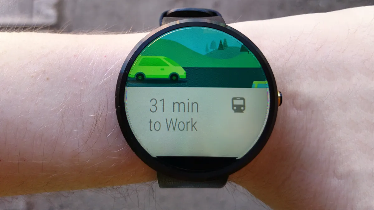 A smartwatch strapped to a wrist. The smartwatch’s screen shows a train symbol next to the text “31 minutes to Work”.