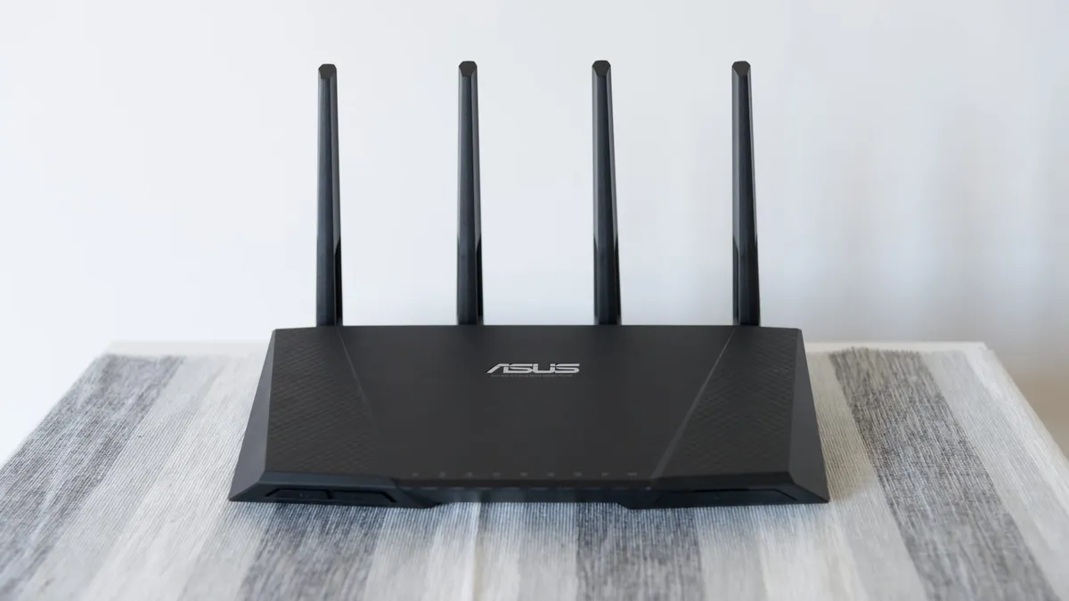 An ASUS ACRT87U Wi-Fi router sitting on a table with its four Wi-Fi antennas pointing upwards.