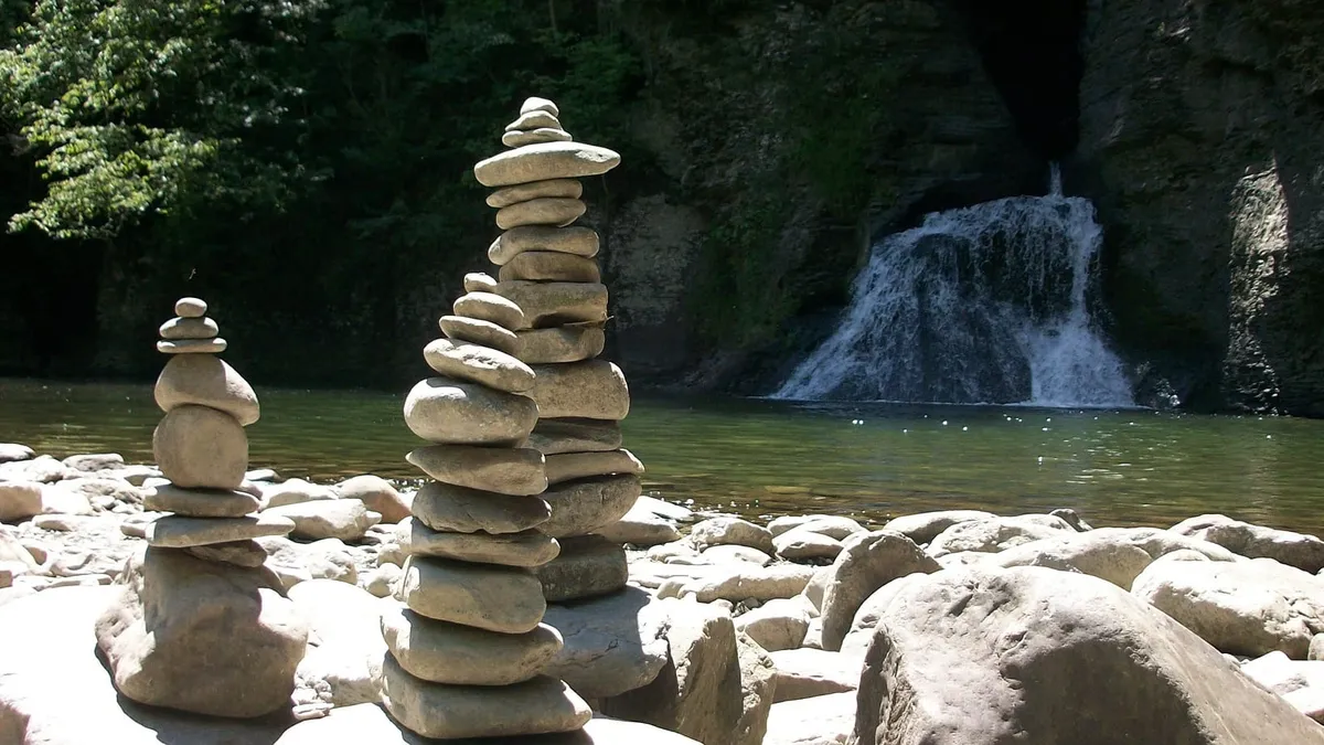 Three stone crains in front of a waterfall.