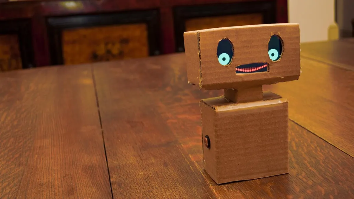 A sad-looking robot made out of cardboard.