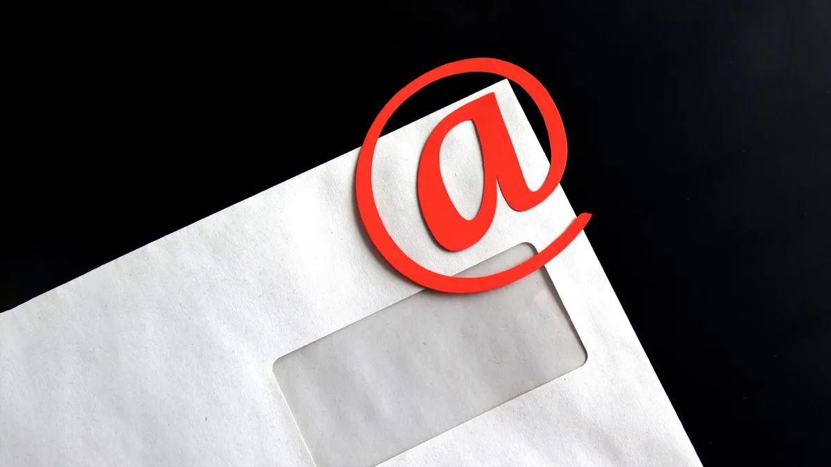 An envelope with a red “@” symbol laying on top of it.
