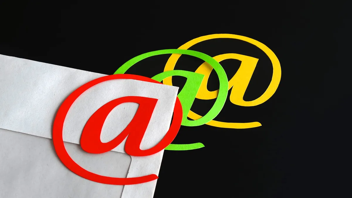 An envelope with three colored “@” symbols laying on top of it.