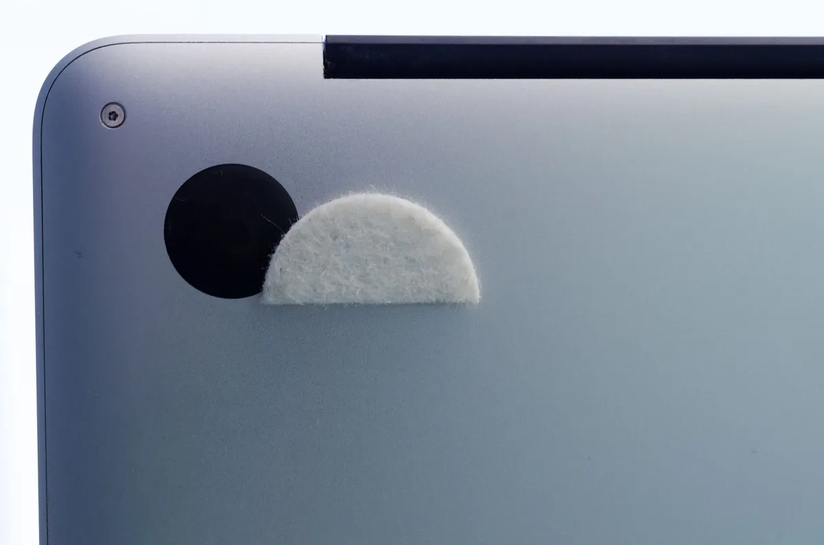 The underside of a MacPro laptop with half a feltpad stuck to its feet.