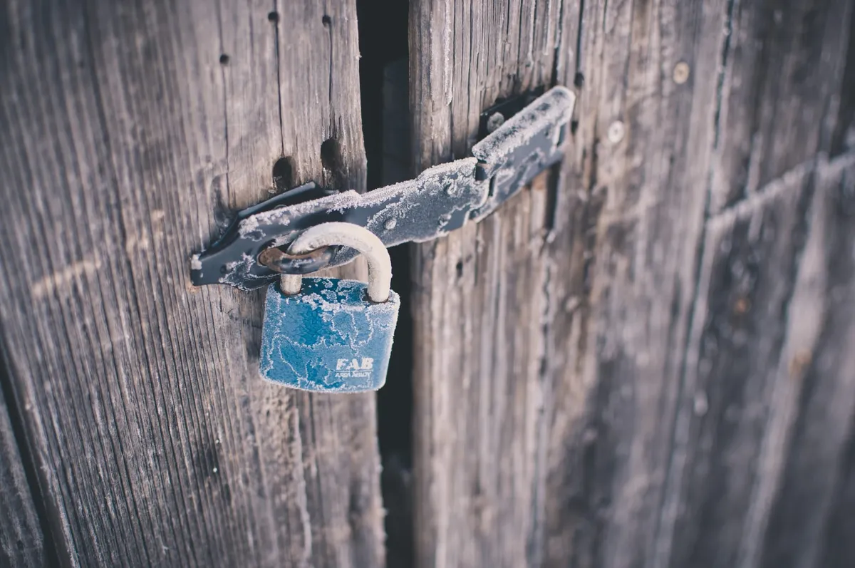A frosted blue padlock securing an old wooden door.