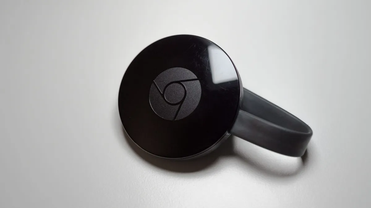 A second-generation Google Chromecast device sitting on a table.