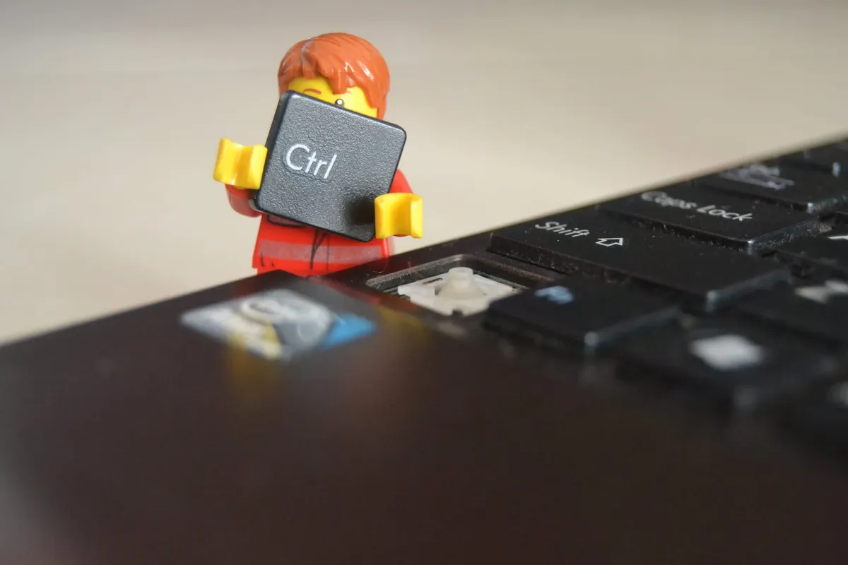 A Lego figurine detaching the Control key off a laptop keyboard.