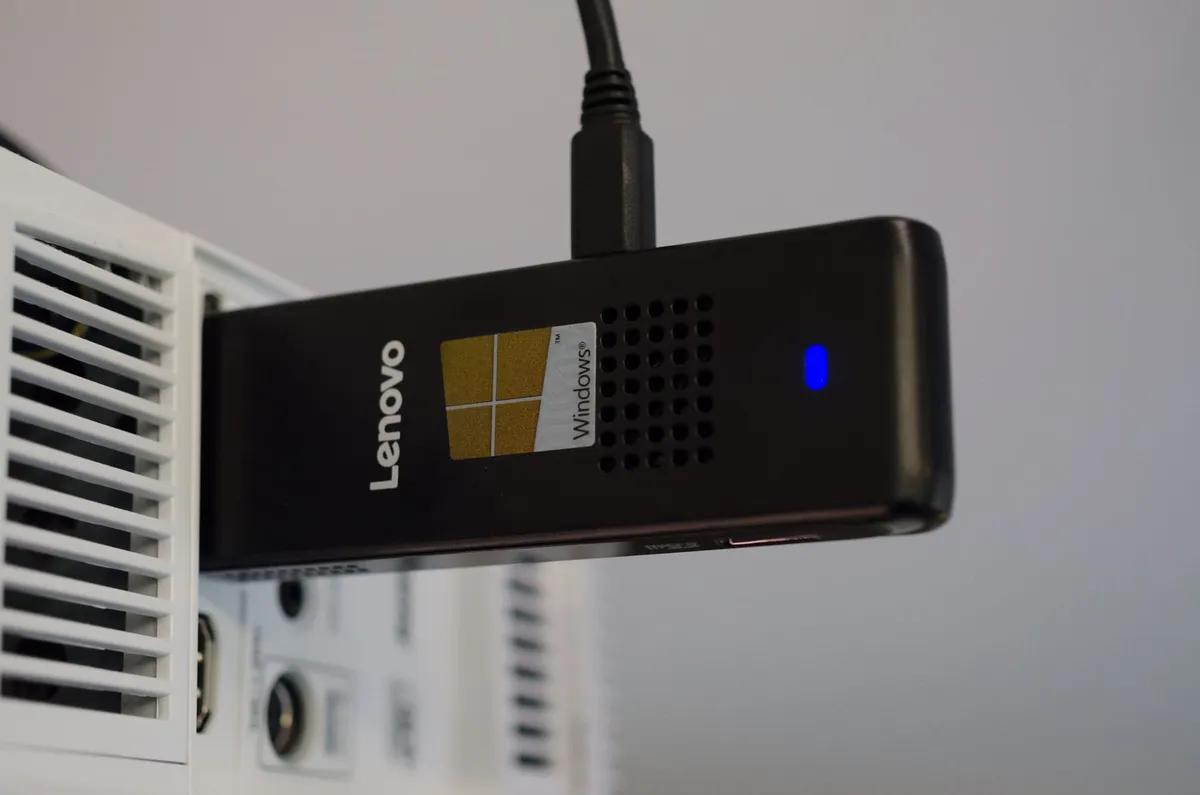 A Lenovo IdeaCentre Stick 300 sticking out of a ceiling-mounted projector.