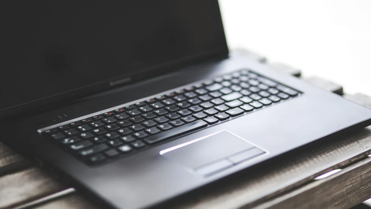 A closeup on the keyboard of a Lenovo laptop with a dark screen.