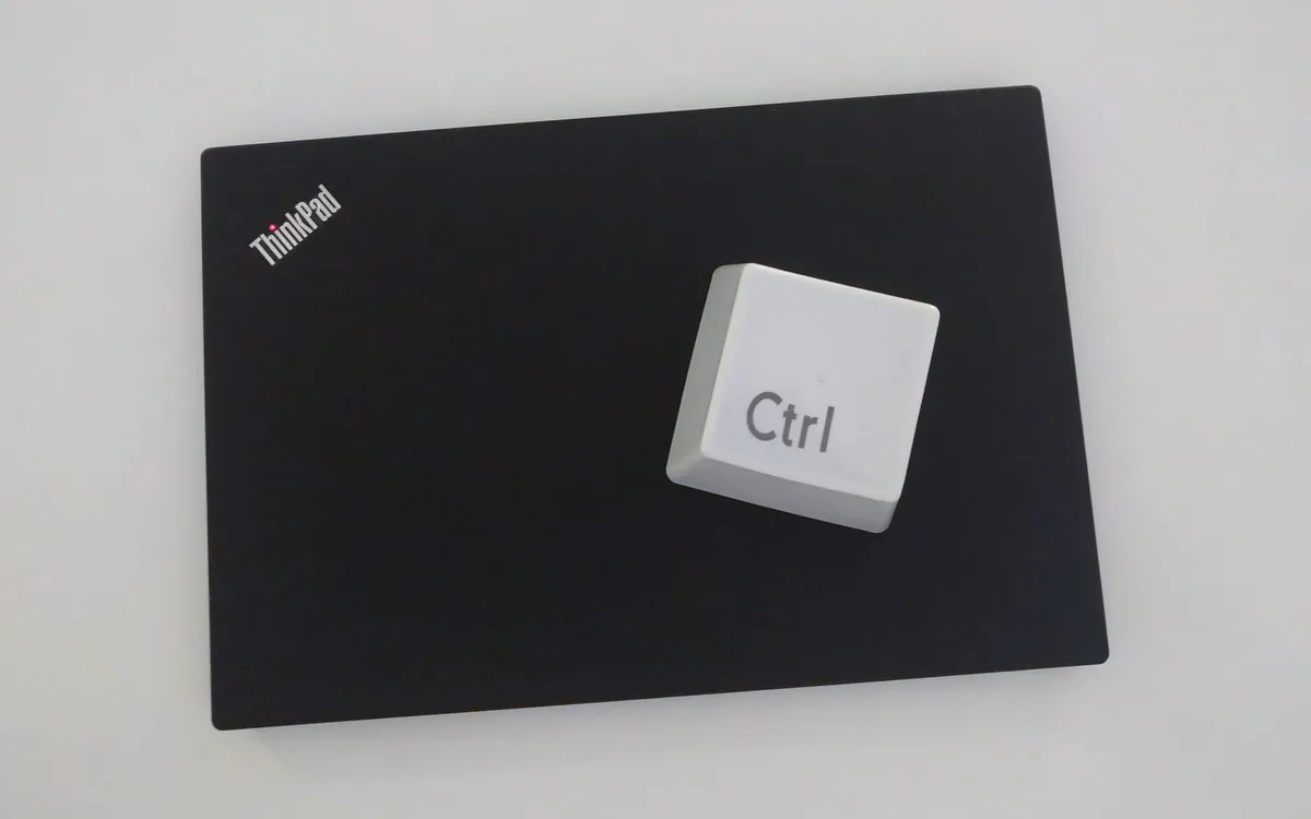 A large white novelty Ctrl computer keyboard key placed on top of a Lenovo ThinkPad laptop.