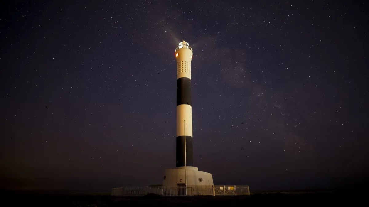 A lighthouse against a stary night sky.