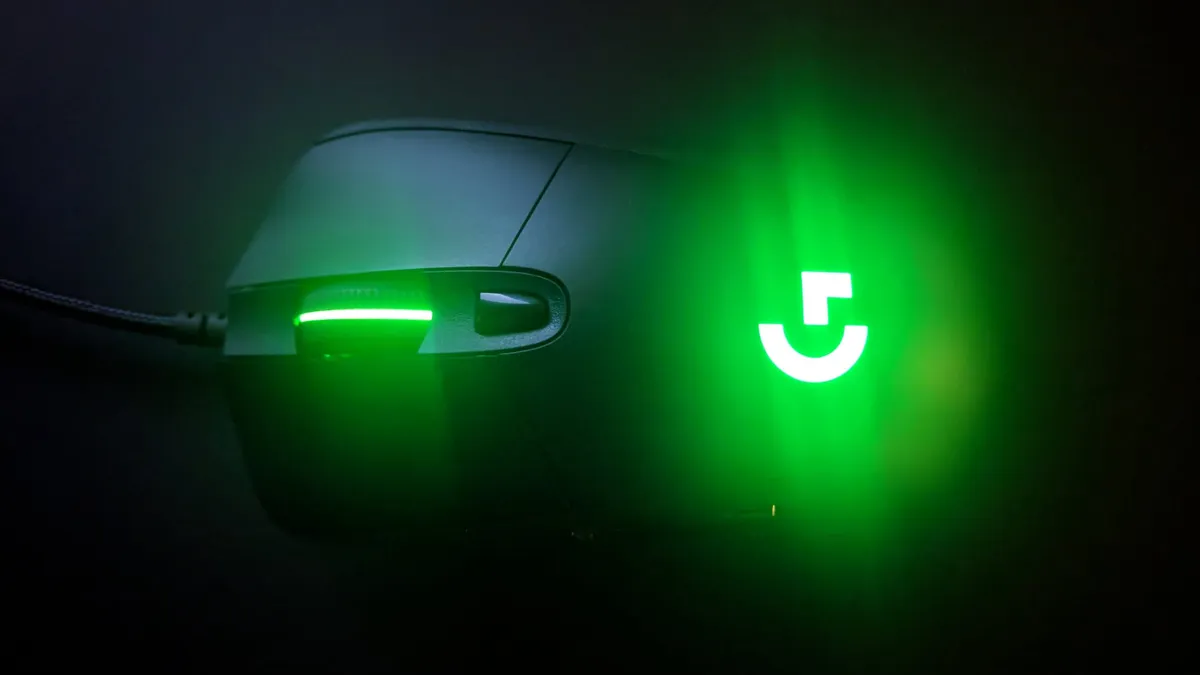 A close-up of a Logitech G403 gaming mouse glowing green in the dark.