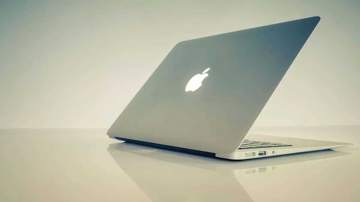 A MacBook laptop resting half-opened on a table.
