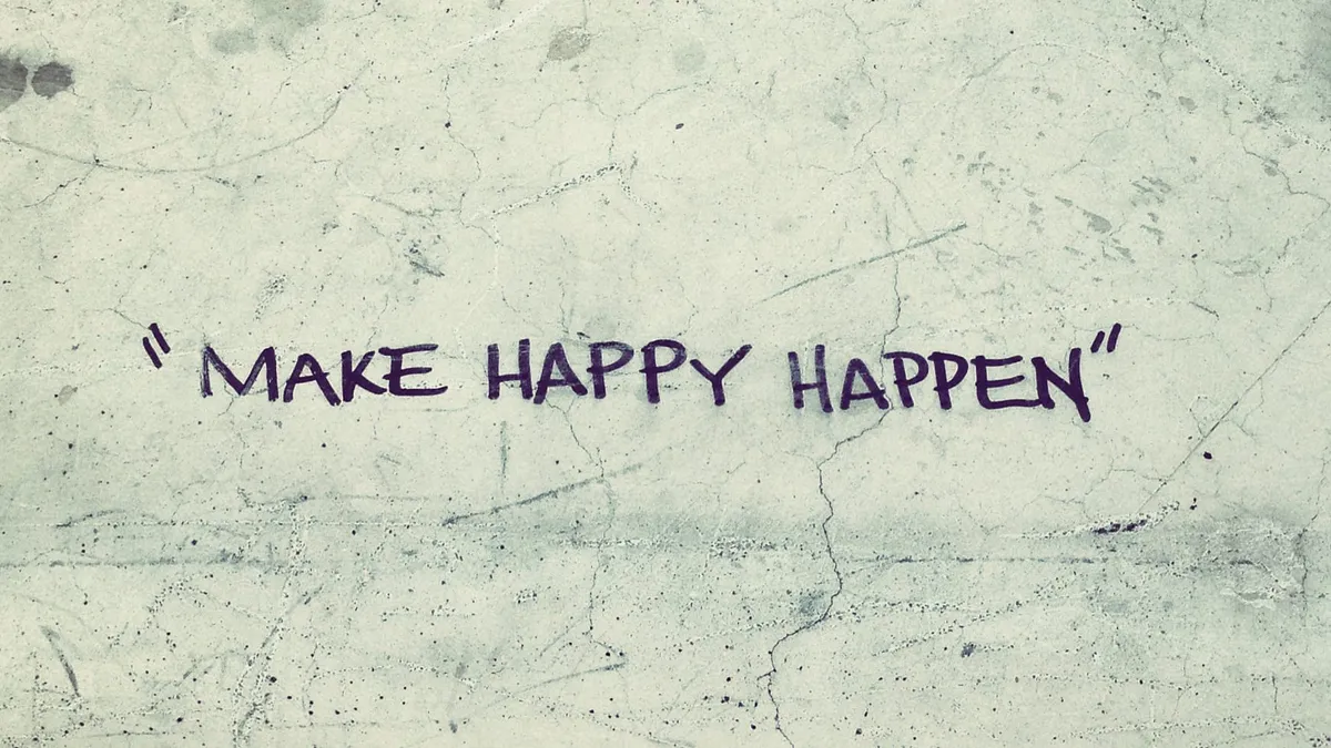 “Make Happy Happen” written on cracked and worn concrete.