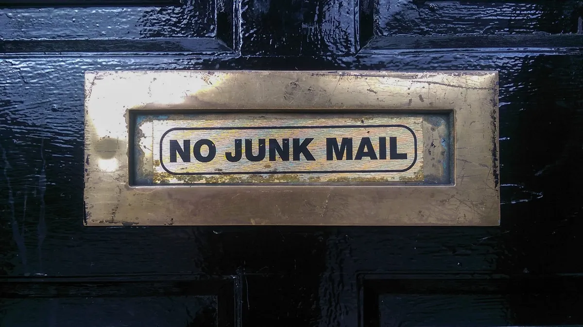 A door mail slot lableled “No Junk Mail”.