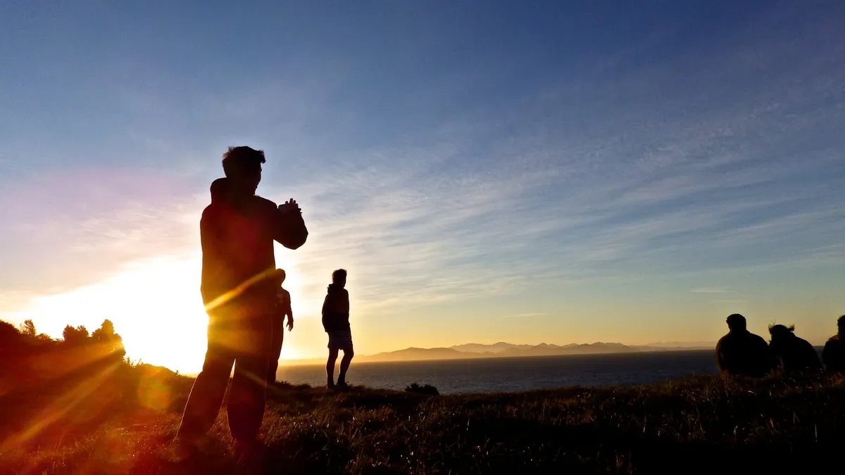 The silhouette of a man photographing a sunset.