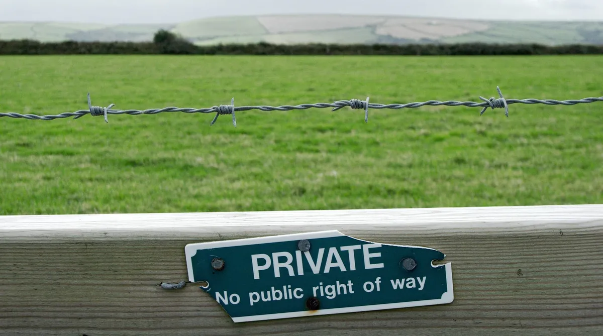 A wooden fence with a worn-out sign saying “Private. No public right of way.”