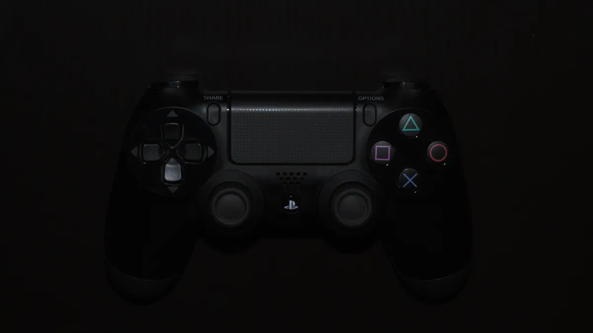 A close-up from above of a PlayStation DualShock 4 controller in the dark.