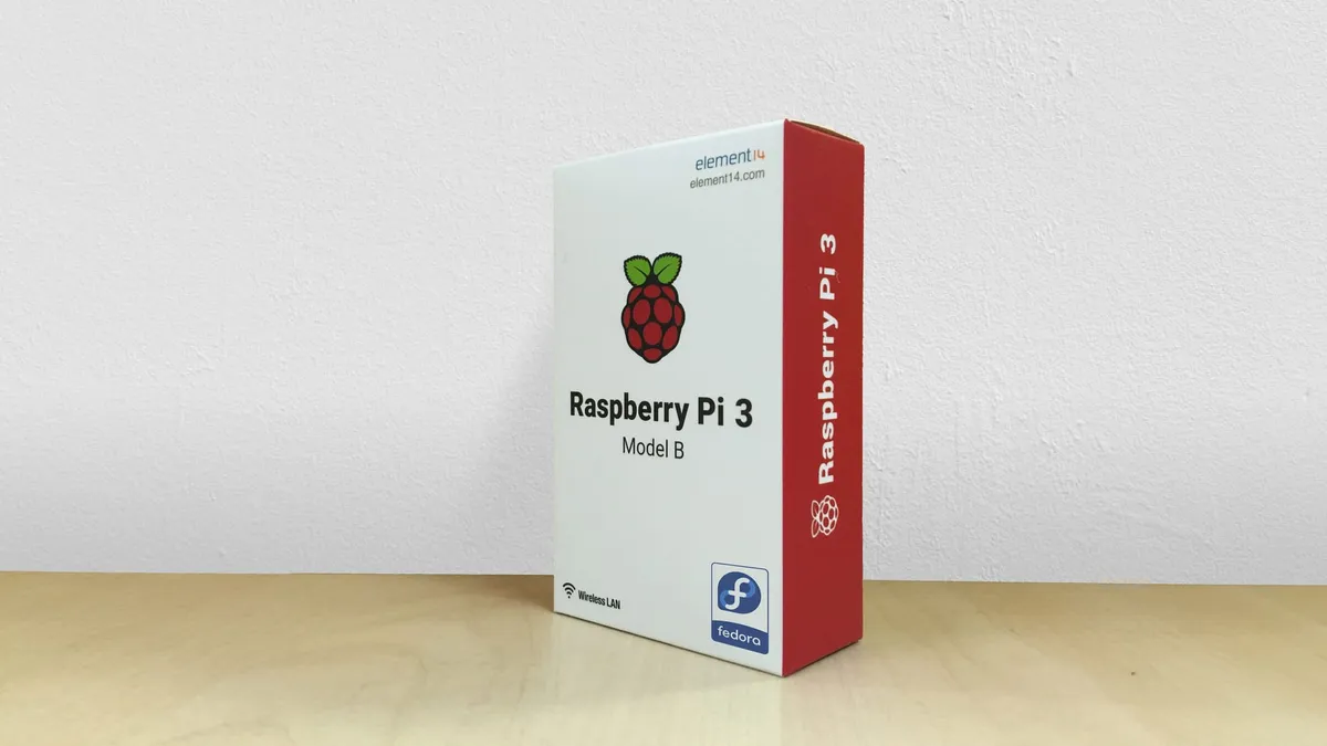 A Raspberry Pi 3 retail box sitting on a table. The box has a small Feodra Linux logo sticker in one corner.