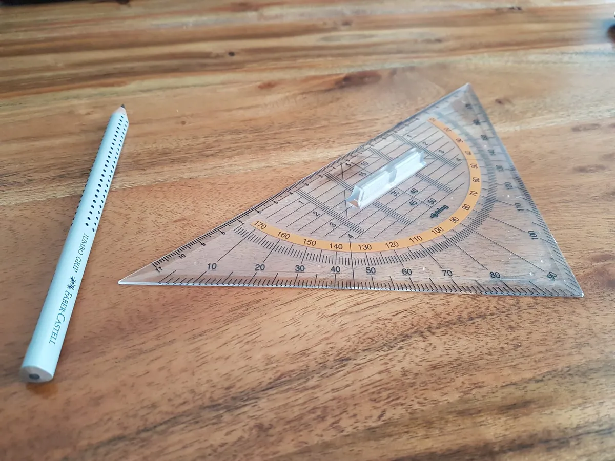 A triangular ruler and gray pencil on a wooden surface.