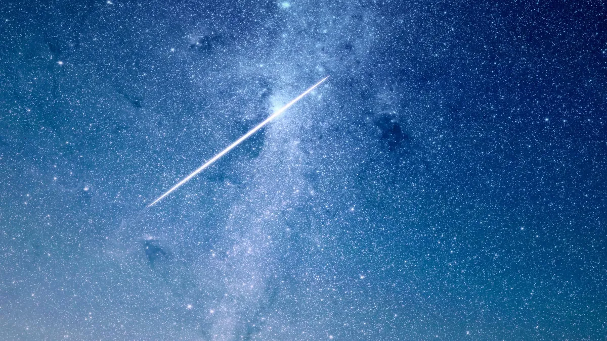 A shooting star against a backdrop of stars at night.