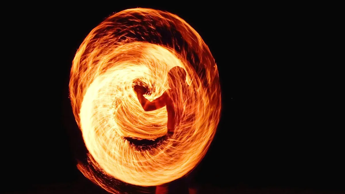A man swirling a torch in front of him forming a wall of fire.