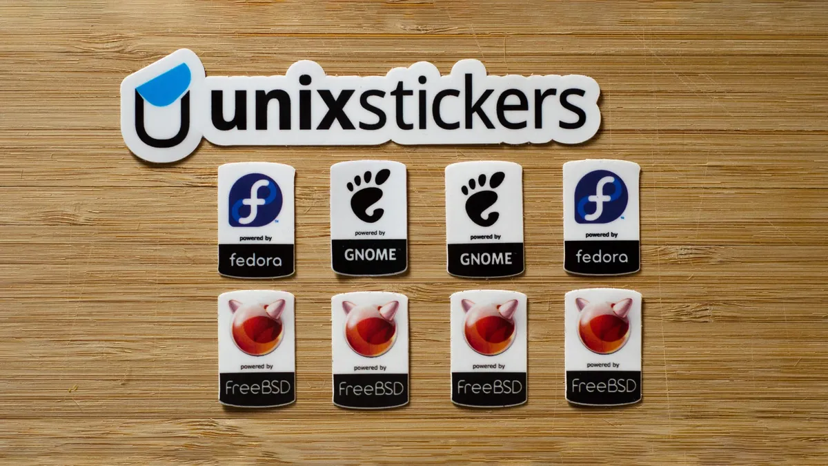 A Unixstickers sticker and a grid of Feodra Linux, GNOME, and FreeBSD stickers.