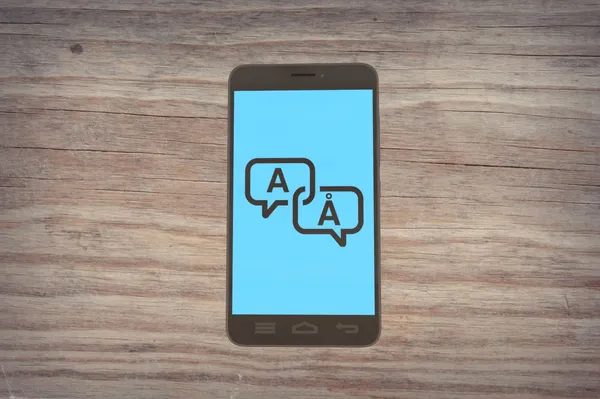 An Android smartphone resting on a table showing two chat bubbles: one with an “A” character and the other “Å” (a-ring) character.