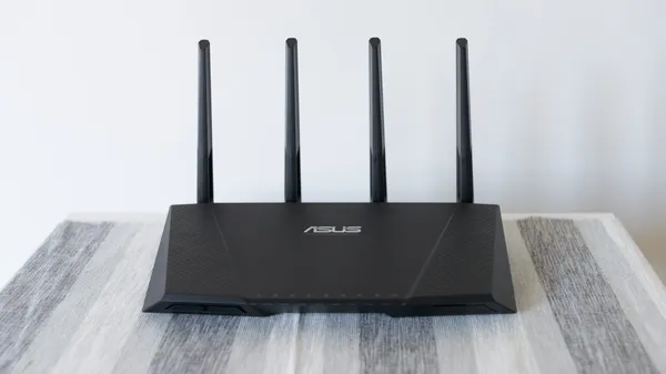 An ASUS ACRT87U Wi-Fi router sitting on a table with its four Wi-Fi antennas pointing upwards.