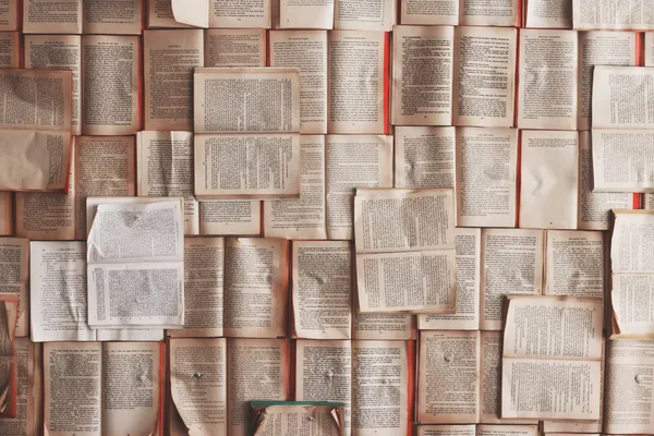 A large number of books laying open and exposing their yellowing pages.