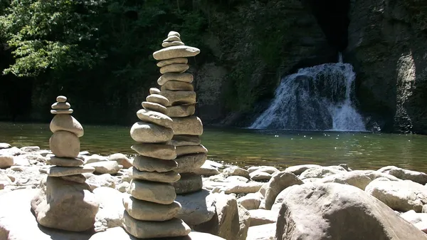 Three stone crains in front of a waterfall.