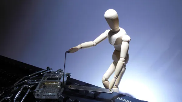 A mini mannequin lockpicking a dummy padlock on top of a computer keyboard.
