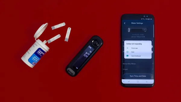 An open box of glucose test strips with a Contour Next glucose meter next to it. Next to that, a smartphone with a view on the screen titled “Meter Settings” overlaid by an error message…