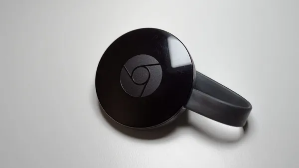 A second-generation Google Chromecast device sitting on a table.