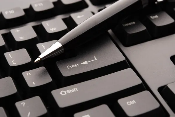 A pen laying on top of the Enter key on a keyboard.