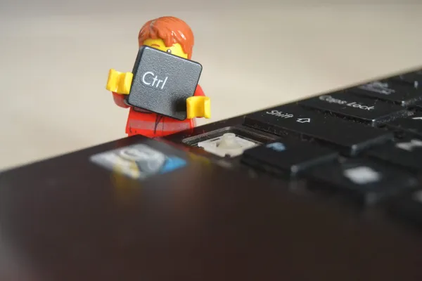 A Lego figurine detaching the Control key off a laptop keyboard.