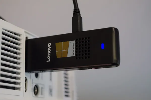 A Lenovo IdeaCentre Stick 300 sticking out of a ceiling-mounted projector.
