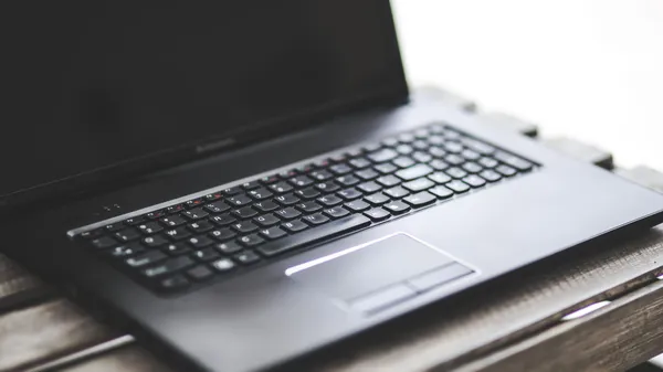A closeup on the keyboard of a Lenovo laptop with a dark screen.