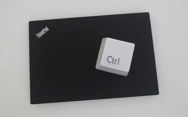 A large white novelty Ctrl computer keyboard key placed on top of a Lenovo ThinkPad laptop.