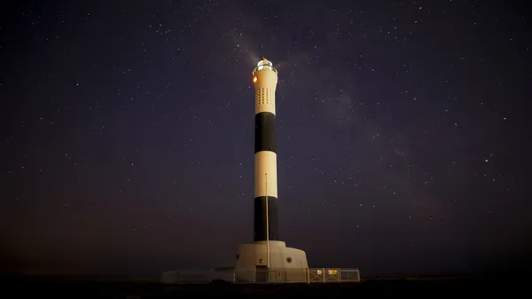 A lighthouse against a stary night sky.