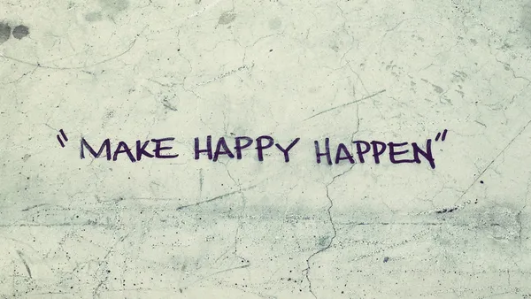 “Make Happy Happen” written on cracked and worn concrete.