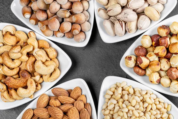 Triangular bowls filled with various nuts arranged in a star-shape.