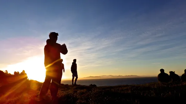 The silhouette of a man photographing a sunset.