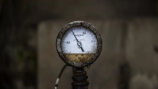 A dirty old mechanical pressure gauge resting at zero.