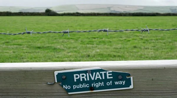 A wooden fence with a worn-out sign saying “Private. No public right of way.”