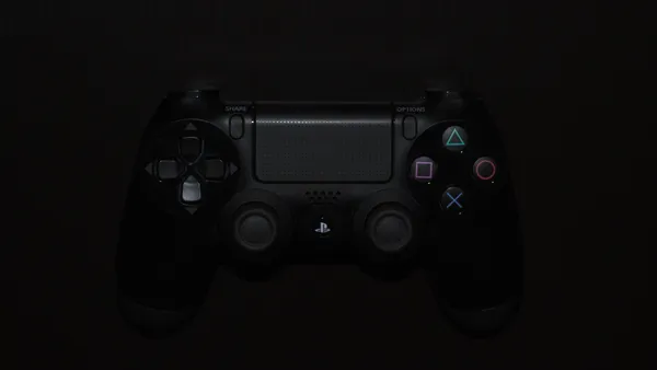 A close-up from above of a PlayStation DualShock 4 controller in the dark.