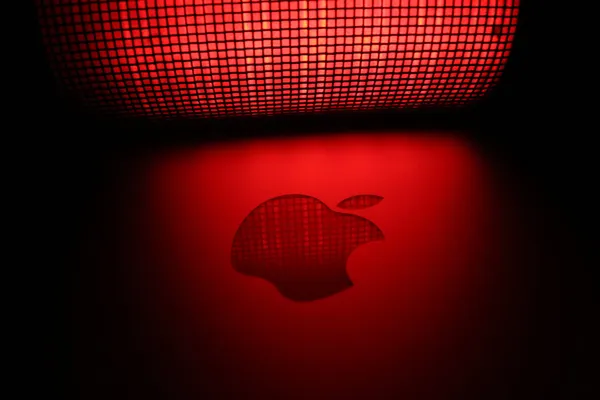 The Apple logo lit up by a red mesh-covered light.