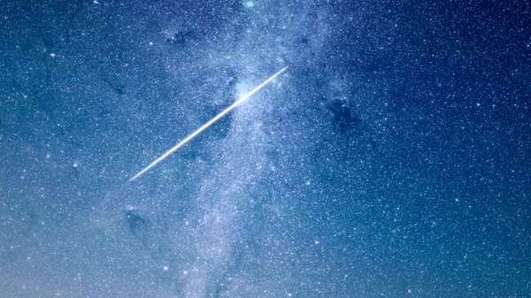 A shooting star against a backdrop of stars at night.