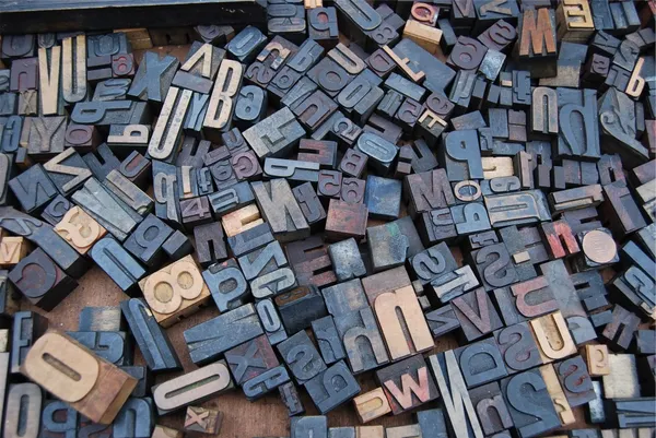 A scattered set of wooden typesetting letters and symbols.