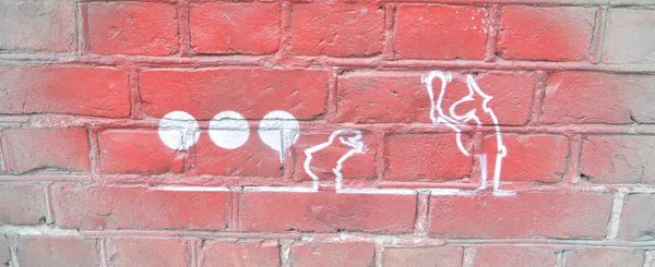 A brick wall with a spray-painted single-line cartoon showing a policeman waving his baton at another character.
