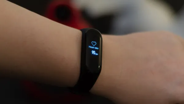 A Xiaomi Mi Band 3 fitness wristband showing a heart rate of 90 bpm.